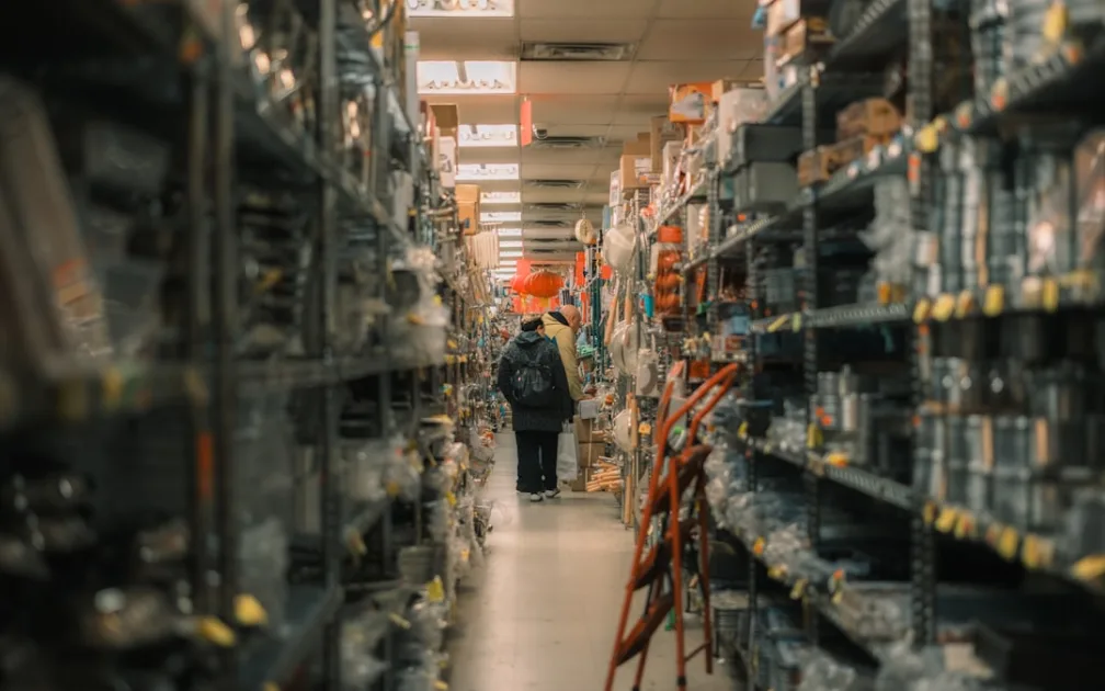 Person walks down aisle of stocked warehouse shelves